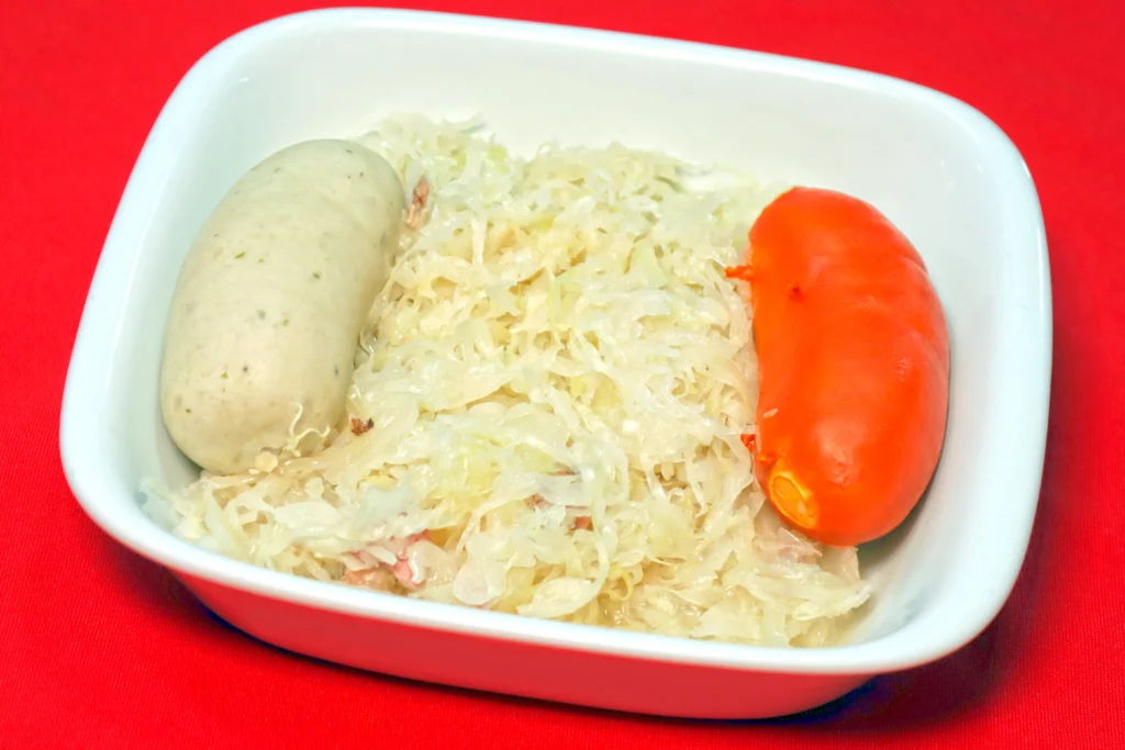 Porção de salsichas alemãs, branca e vermelha, acompanhadas de chucrute.
